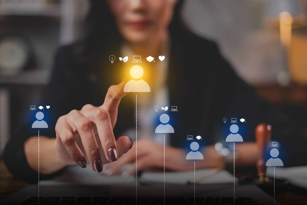 Femme sélectionnant un profil candidat virtuel lumineux avec des icônes d'idées, compétences, éducation et valeurs. Recrutement ciblé.